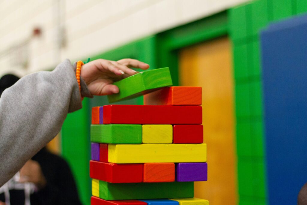 Görselde dikkat eksikligini anlatmak için lego oynayan bir çocuk eli var.